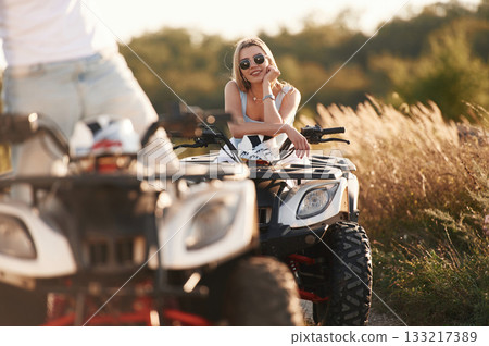 Countryside road, front view. Man and woman are on ATV outdoors 133217389