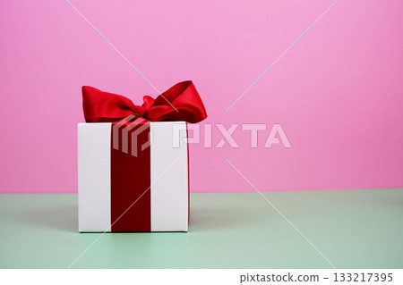 Gift Box with red ribbon on pink and green background 133217395