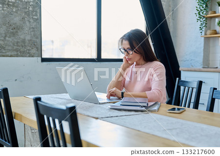 Middle aged woman having video conference on laptop sitting at desk 133217600