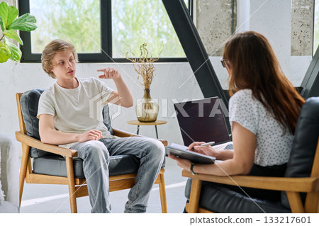 Teenage boy talking to female professional psychologist counselor therapist Teenage boy talking to female professional psychologist counselor therapist 133217601
