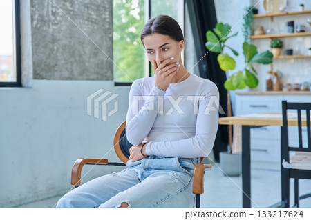 Sad upset teenager girl sitting at home in living room 133217624