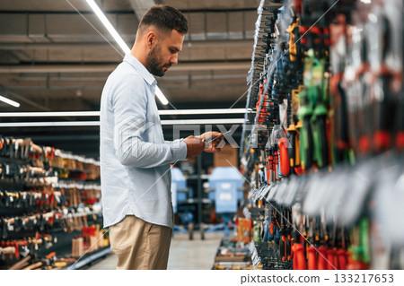 Searching for the tools. Man is in the hardware shop Searching for the tools. Man is in the hardware shop 133217653