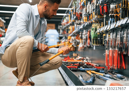 With garden shears. Man is in the hardware shop With garden shears. Man is in the hardware shop 133217657