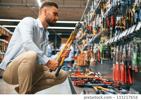With garden shears. Man is in the hardware shop With garden shears. Man is in the hardware shop 133217658