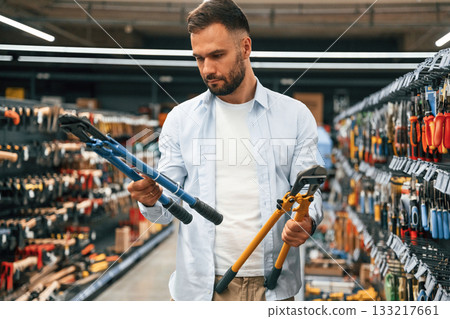 With garden shears. Man is in the hardware shop With garden shears. Man is in the hardware shop 133217661