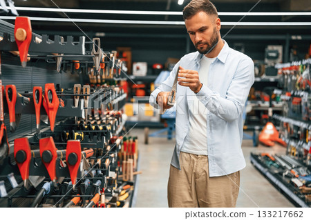Picking an axe. Man is in the hardware shop 133217662