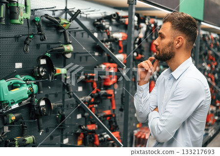Big choice of drills. Man is in the hardware shop Big choice of drills. Man is in the hardware shop 133217693