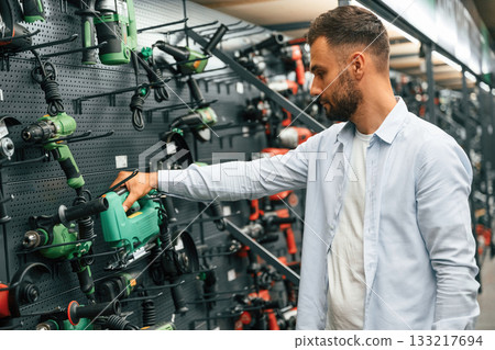 Big choice of drills. Man is in the hardware shop Big choice of drills. Man is in the hardware shop 133217694