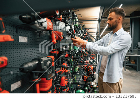 Big choice of drills. Man is in the hardware shop 133217695