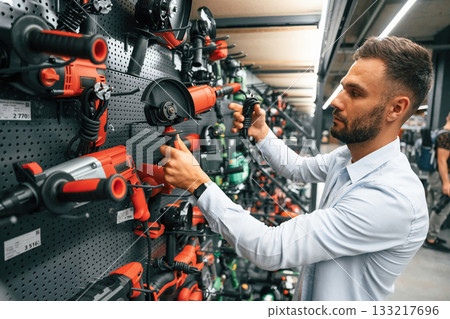 Selecting the new equipment. Man is in the hardware shop 133217696
