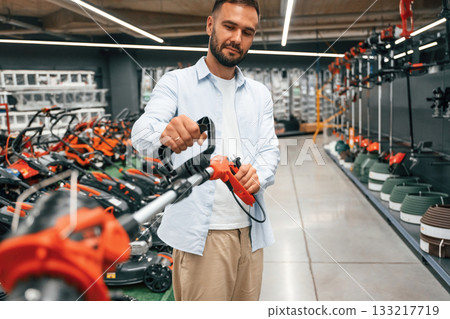 Grass trimmer in hands. Man is in the hardware shop Grass trimmer in hands. Man is in the hardware shop 133217719