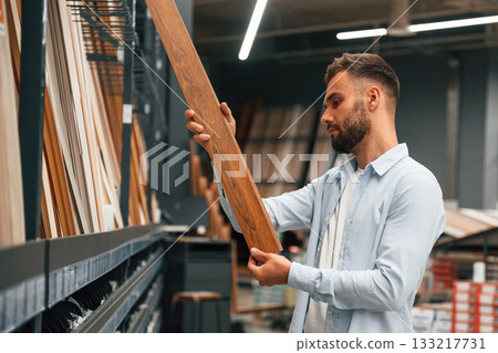 Parquet, choosing. Man is in the hardware shop Parquet, choosing. Man is in the hardware shop 133217731
