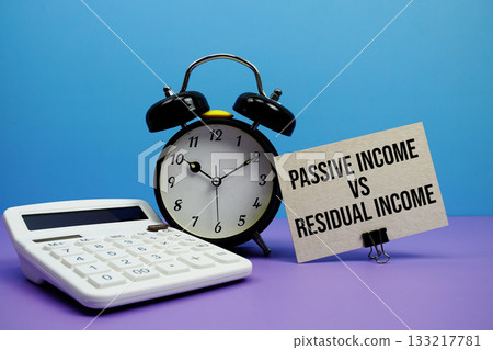 Passive Income VS Residual Income text with calculator and alarm clock on blue and purple background 133217781