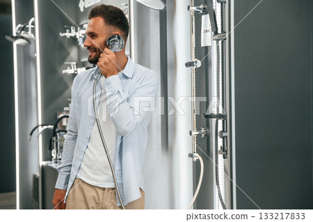 Talking by showerhead, having fun, joking. Man is in the hardware shop 133217833