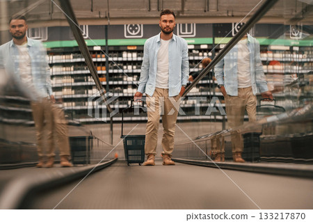 Handsome man is on the escalator in the mall 133217870