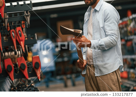 An axe in hands. Man is in the hardware shop 133217877