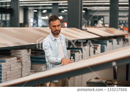 Warehouse with big choice of parquet. Man is in the hardware shop Warehouse with big choice of parquet. Man is in the hardware shop 133217888