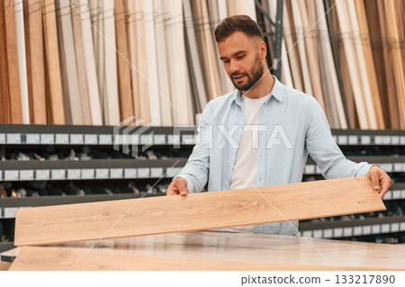 Warehouse with big choice of parquet. Man is in the hardware shop 133217890