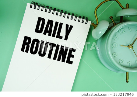 Daily Routine text with alarm clock flat lay on green background 133217946