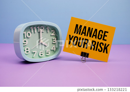 Manage Your Risk text and alarm clock on blue and purple background Manage Your Risk text and alarm clock on blue and purple background 133218221