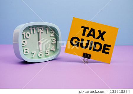 Tax Guide text and alarm clock on blue and purple background 133218224
