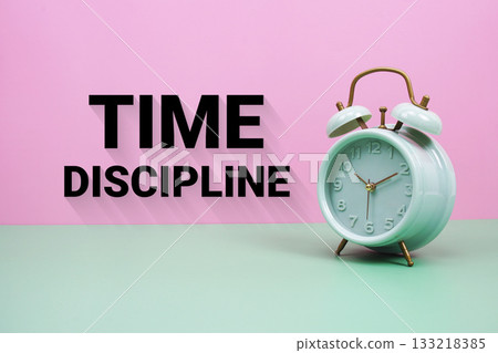 Black alarm clock on a pastel green and pink background with the text "Time Discipline" 133218385