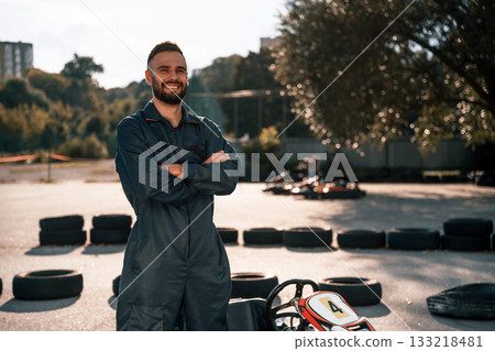 Standing against vehicle and trees. Man is outdoors, kart racing conception 133218481