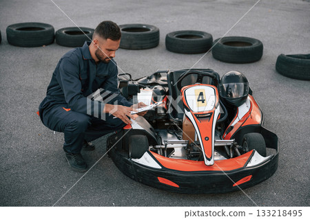 With notepad in hands. Man is outdoors, kart racing conception 133218495