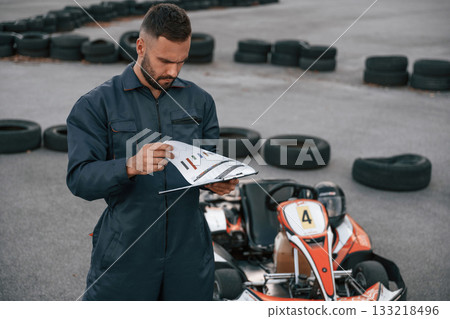 With notepad in hands. Man is outdoors, kart racing conception 133218496