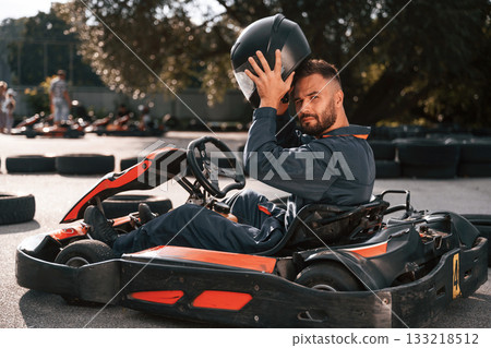 Wearing the safety helmet. Man is outdoors, kart racing conception Wearing the safety helmet. Man is outdoors, kart racing conception 133218512