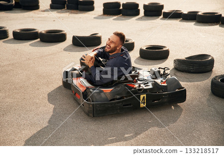 Looks behind while riding. Man is outdoors, kart racing conception 133218517