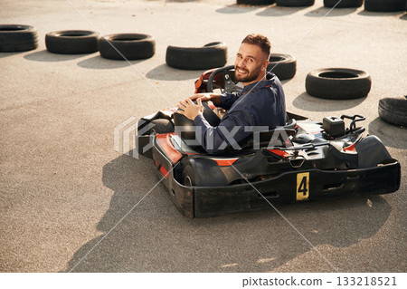 Riding and looking behind. Man is outdoors, kart racing conception 133218521