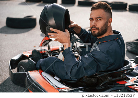Riding and looking behind. Man is outdoors, kart racing conception 133218527