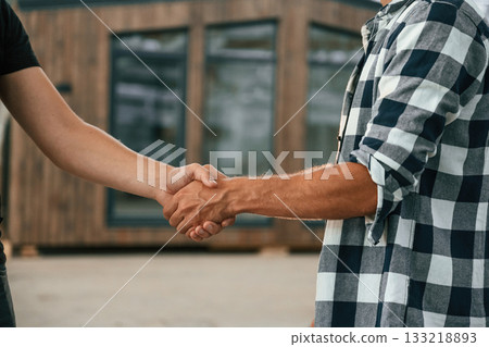 Agreement, handshake. Two workers are in the industrial wooden warehouse Agreement, handshake. Two workers are in the industrial wooden warehouse 133218893