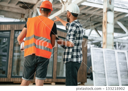 Builder is talking with manager or architect. Two workers are in the industrial wooden warehouse Builder is talking with manager or architect. Two workers are in the industrial wooden warehouse 133218902