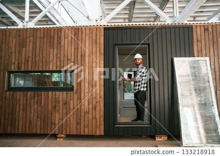 Showing the wooden house that is under construction. Industrial worker in warehouse 133218918