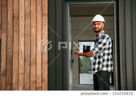 Showing the wooden house that is under construction. Industrial worker in warehouse 133218919