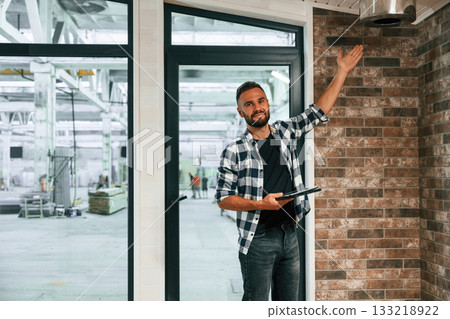 Showing the wooden house that is under construction. Industrial worker in warehouse Showing the wooden house that is under construction. Industrial worker in warehouse 133218922