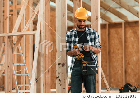 With the drill. Industrial worker in wooden warehouse With the drill. Industrial worker in wooden warehouse 133218935