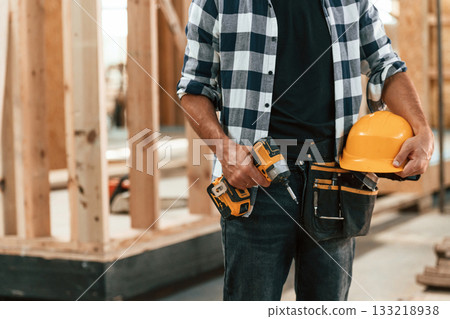 With the drill. Industrial worker in wooden warehouse 133218938
