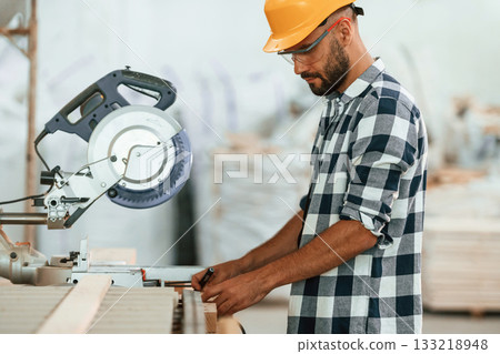 Cutting the wood. Industrial worker in the warehouse 133218948
