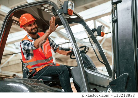 Driving the forklift. Industrial worker in wooden warehouse 133218958