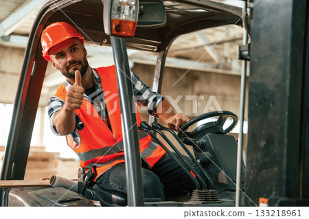 Sitting in the forklift. Industrial worker in wooden warehouse Sitting in the forklift. Industrial worker in wooden warehouse 133218961