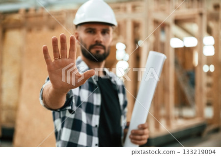 Stop hand gesture, no trespassing. Industrial worker in wooden warehouse Stop hand gesture, no trespassing. Industrial worker in wooden warehouse 133219004