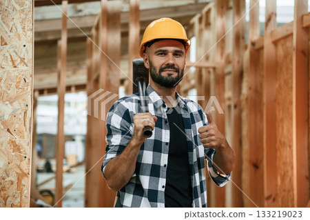 Hammer in hand. Industrial worker in wooden warehouse Hammer in hand. Industrial worker in wooden warehouse 133219023