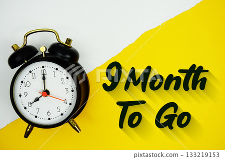 9 Month To Go text and alarm clock on yellow background 133219153