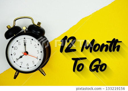 12 Month To Go text and alarm clock on yellow background 12 Month To Go text and alarm clock on yellow background 133219156