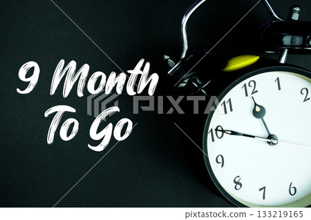 9 Month To Go text and alarm clock on black background 9 Month To Go text and alarm clock on black background 133219165