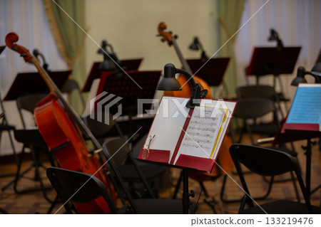 Orchestra rehearsal setting with music stands and instruments before performance Orchestra rehearsal setting with music stands and instruments before performance 133219476