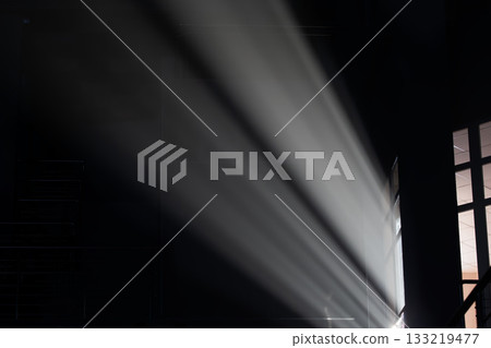 Light beams shining through an open door in a dark room 133219477